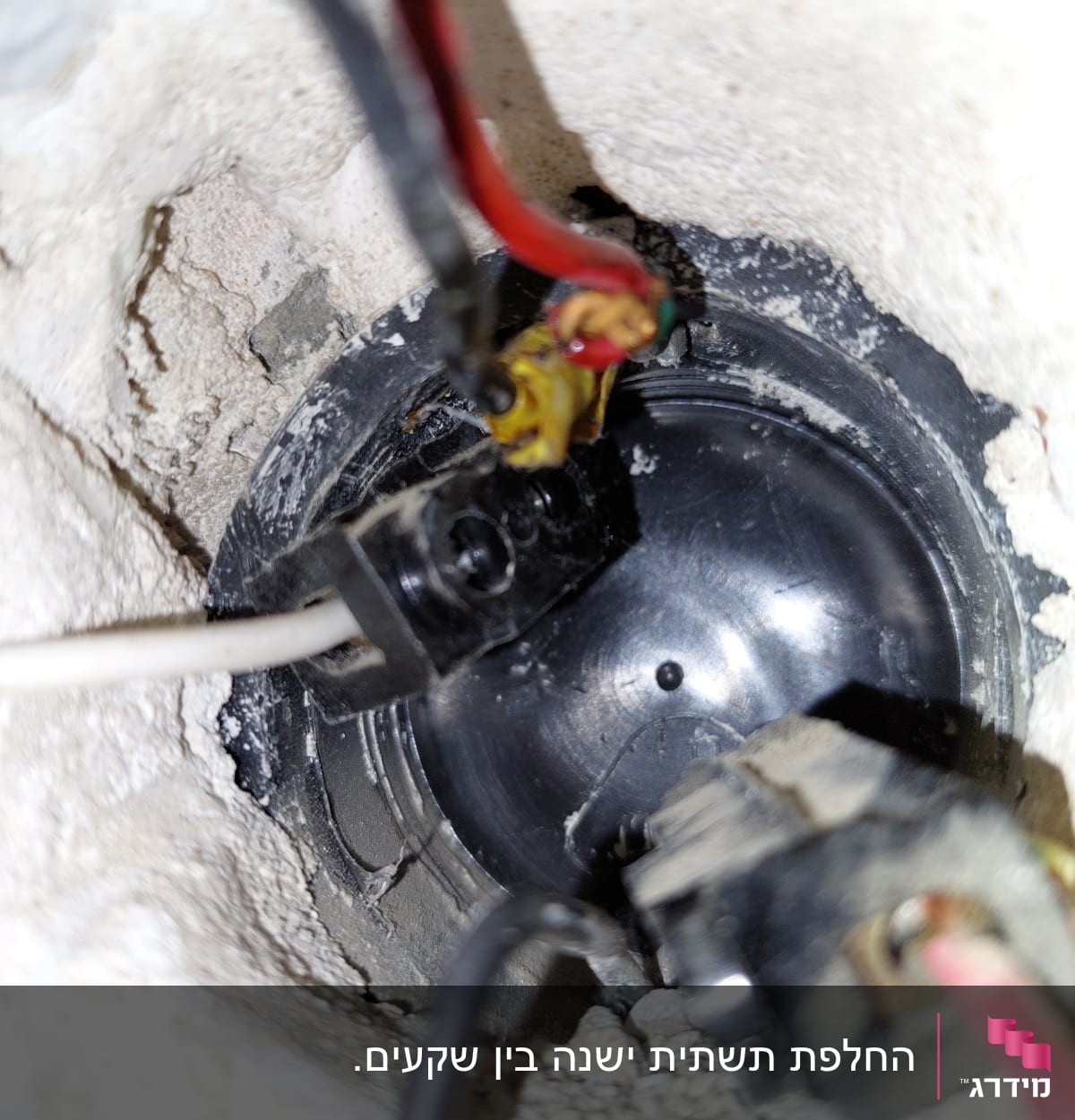 חוטי חשמל מחוברים לקופסת חיבורים בקיר